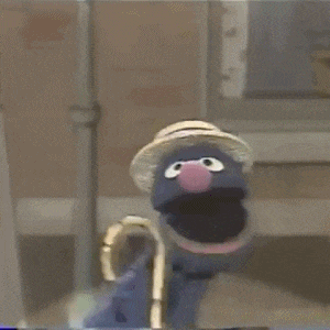 elmo from sesame street is standing next to a faucet and smiling .