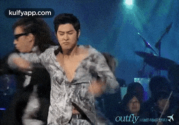 a man without a shirt is dancing on a stage in front of a crowd ..