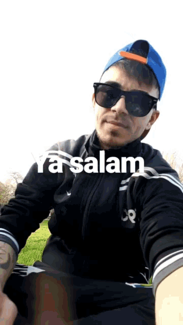 a man wearing sunglasses and a blue hat with the words ya salam written on the bottom