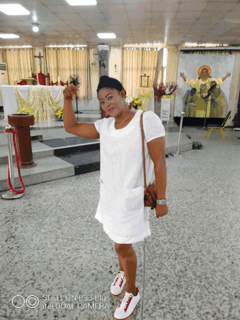 a woman in a white dress is standing in front of a painting of jesus on the wall
