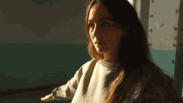 a woman with long hair is standing in front of a window in a room .
