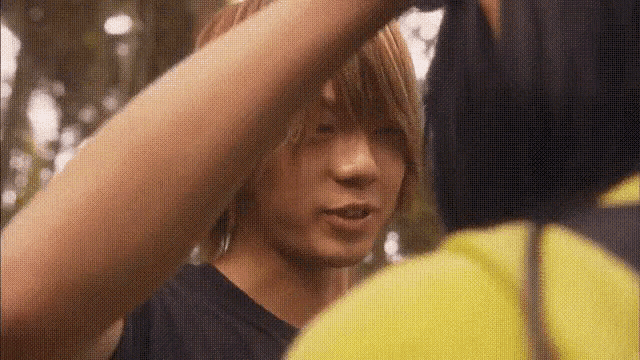 a man in a black shirt is standing next to another man in a yellow jacket .