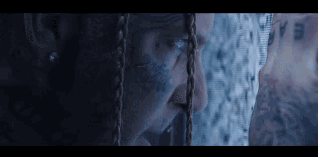 a close up of a person 's face with dreadlocks and tattoos