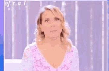 a woman in a pink lace top is making a funny face .