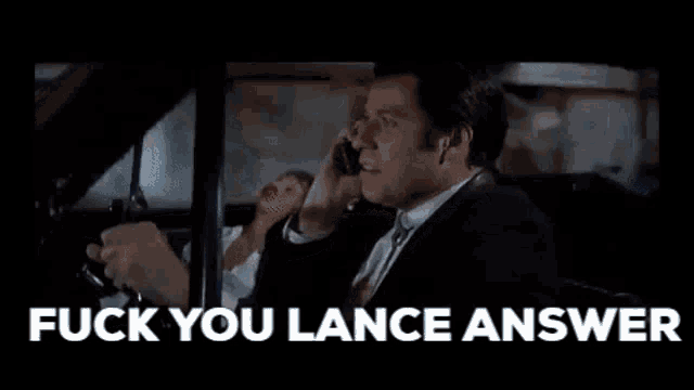 a man in a suit and tie is talking on a cell phone while driving a car .