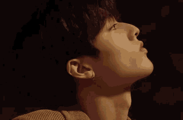 a close up of a man 's face with his mouth open and earring in his ear .