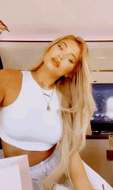 a woman wearing a white crop top and a necklace with the letter j on it