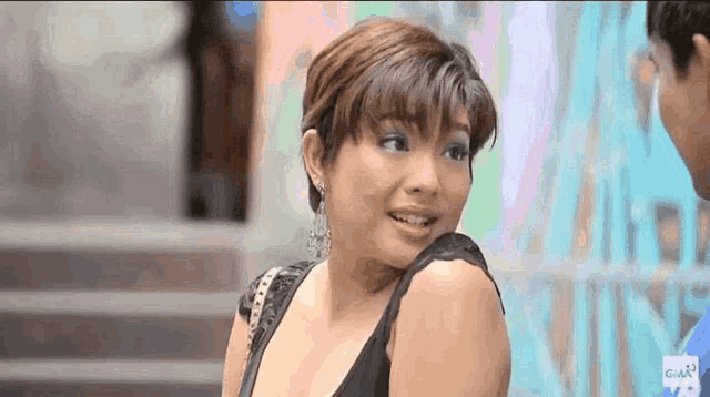 a woman in a black top is smiling and looking at the camera .