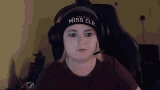a woman wearing headphones and a beanie is sitting in a chair in front of a computer screen .