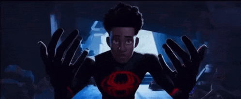 a man in a superhero costume is standing in a dark room surrounded by people .