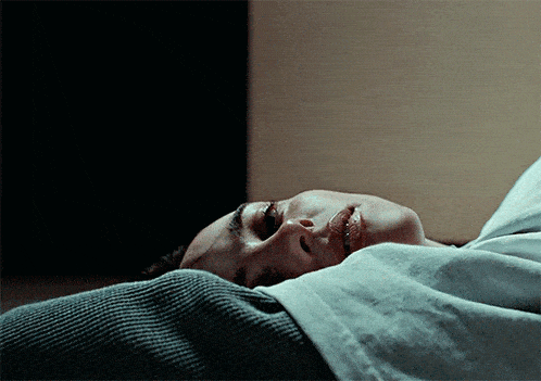 a close up of a woman laying in bed with her eyes closed