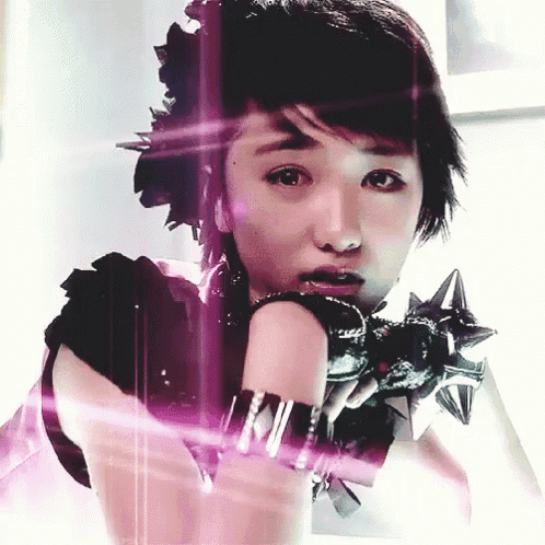 a woman wearing a black top and spiked gloves looks at the camera