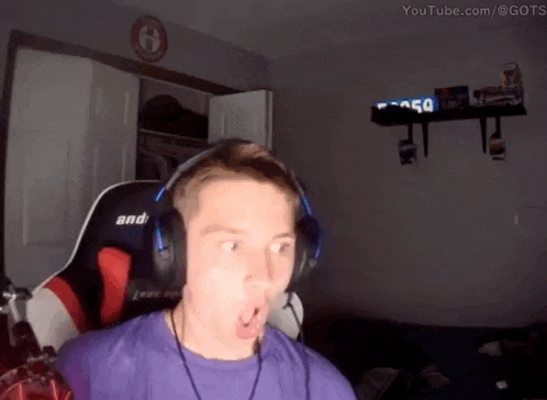 a man wearing headphones is making a funny face while sitting in a gaming chair .