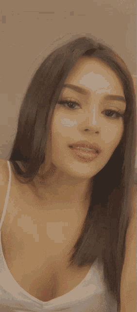 a woman sticking her tongue out in a white tank top