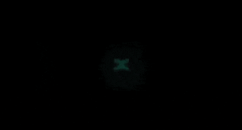 a green x is glowing in the dark in a black circle .