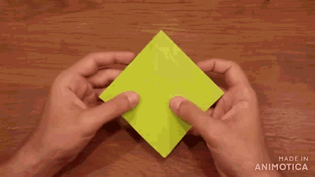 a person is holding a green origami piece in their hands .