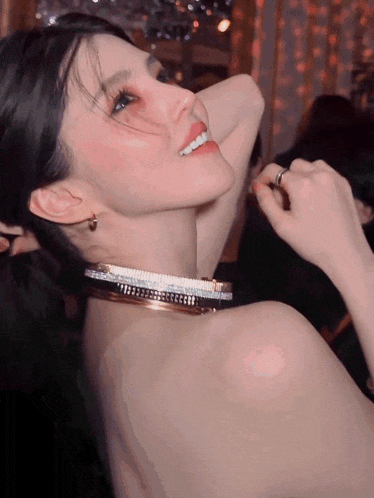a woman with a choker around her neck smiles