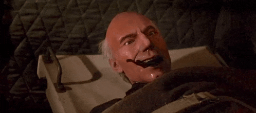 a bald man with a red face is laying in a bed with his mouth open .