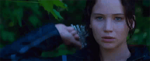 a woman is holding a bow and arrow in her hand and looking at the camera .