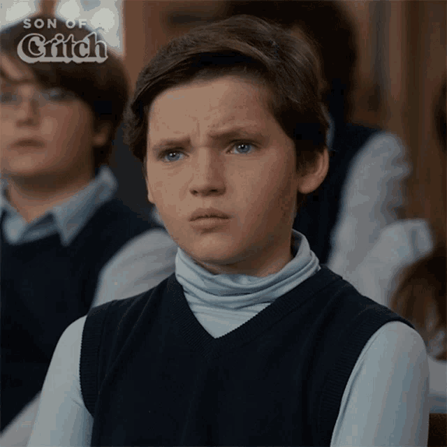 a young boy is sitting in a classroom with the words son of a glitch on the bottom