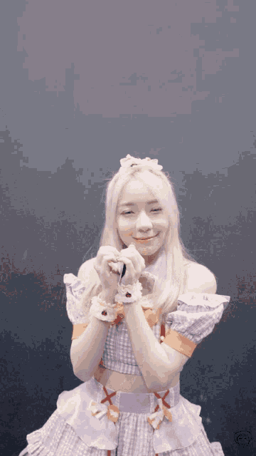 a girl in a purple dress is making a heart with her hands in front of her face