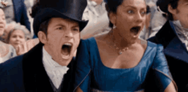 a man in a top hat and a woman in a blue dress are screaming in a crowd of people .