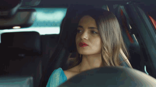 a woman sitting in a car with red lipstick on her lips