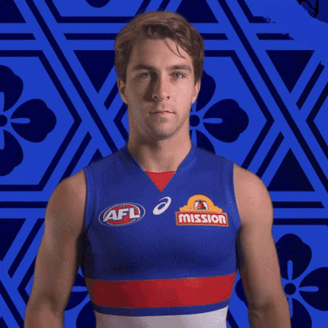 a man wearing a blue shirt with afl and mission logos on it