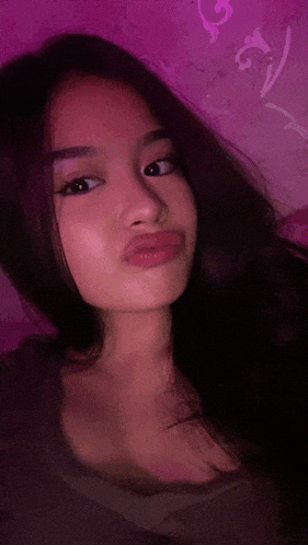 a young woman is taking a selfie in front of a purple background .