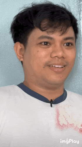 a man wearing a white shirt with a blue collar and a microphone on his neck is smiling