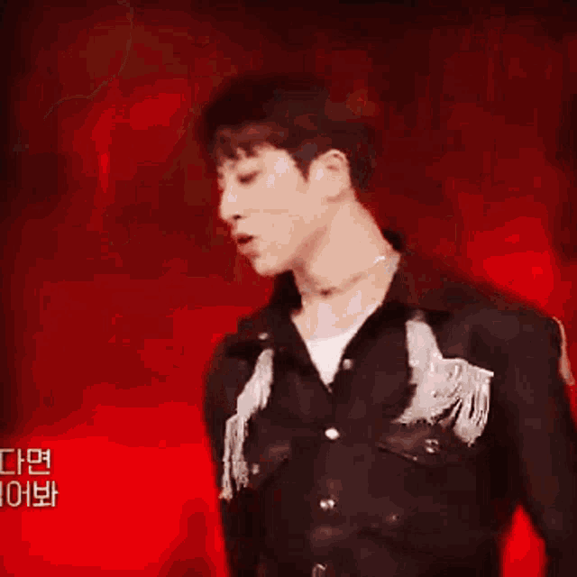 a man in a white shirt and black jacket is dancing on a stage with a red background