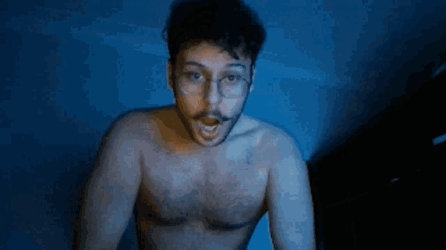 a shirtless man with glasses looks surprised
