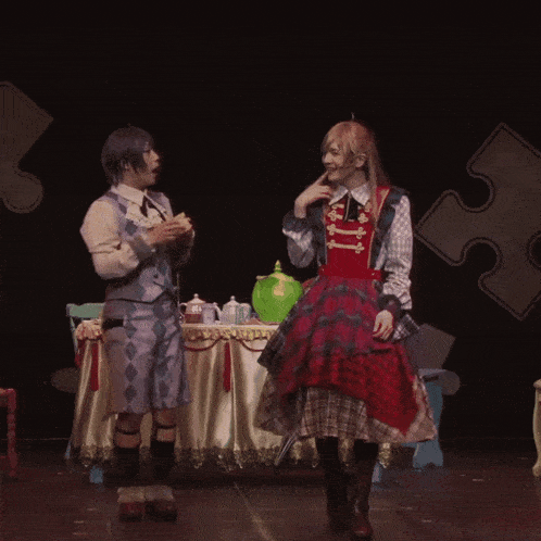 a man and a woman are dancing on a stage in front of a table