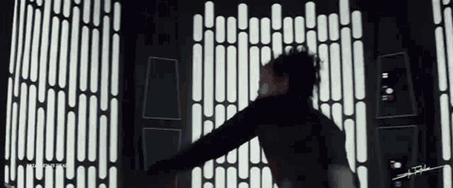a man in a black jacket is standing in front of a wall with white stripes and a sign that says star wars