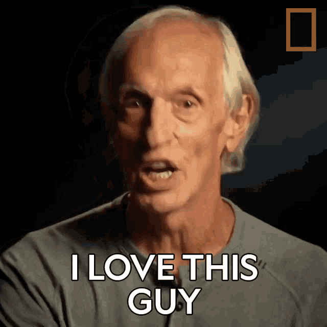 an older man says " i love this guy " in a dark room