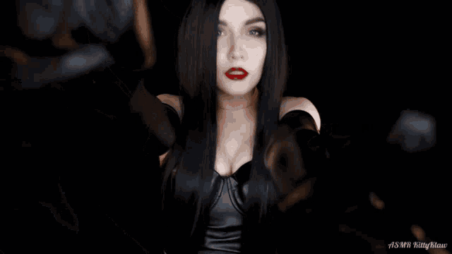 a woman with long black hair and red lipstick is wearing a black dress and gloves
