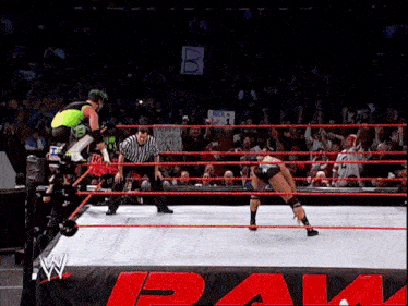 a wrestling match is being played in front of a crowd and a sign that says b