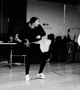 a black and white photo of a woman dancing in front of a mirror
