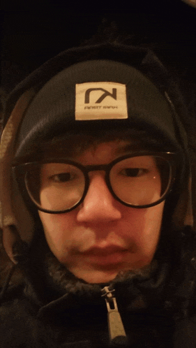 a man wearing glasses and a black beanie with a white patch that says n on it