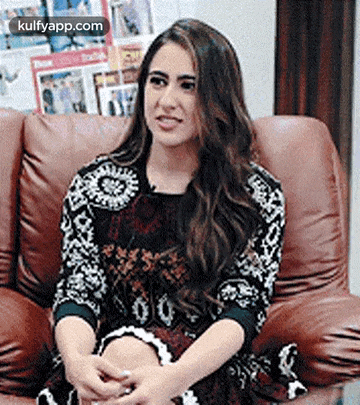 a woman is sitting on a couch with her legs crossed and making a funny face .