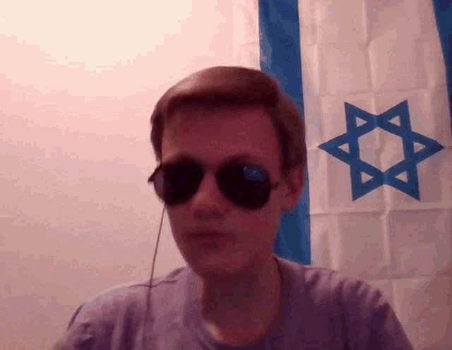 a man wearing sunglasses in front of a flag with a star on it