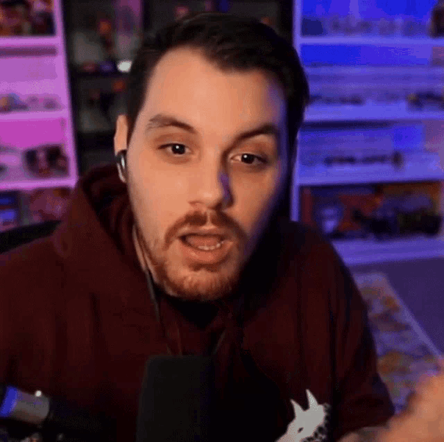 a man in a maroon hoodie is talking into a microphone .