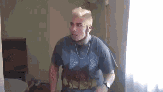 a man is standing in a room wearing a captain america shirt and a chain around his neck .