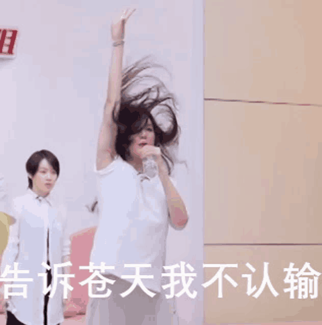 a woman in a white shirt is holding a water bottle in her mouth