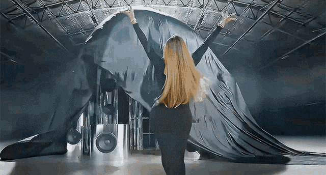 a woman is standing in front of a giant black object
