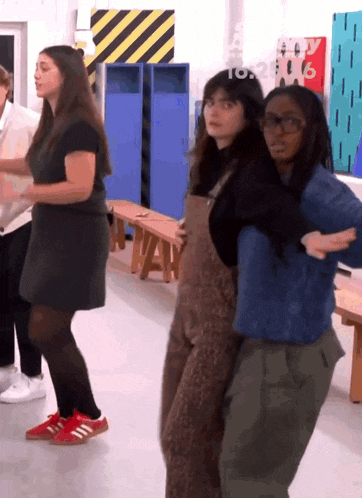 a group of young women are dancing in a room with a sign that says ' a ' on it