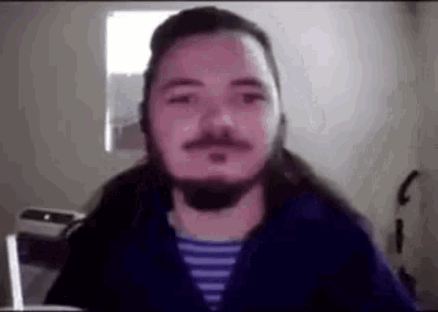 a man with a beard and long hair is wearing a headset while sitting in front of a computer screen .