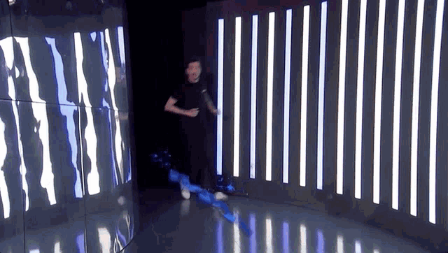 a man in a black shirt is running through a dark room with striped lights