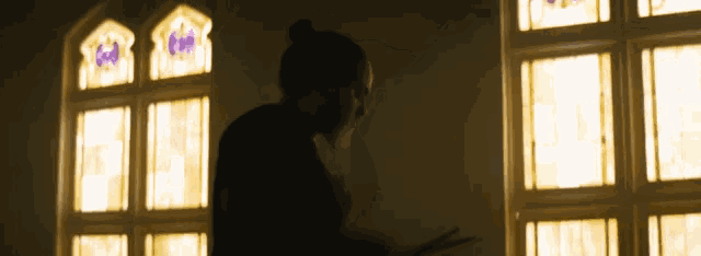 a silhouette of a man standing in front of a window