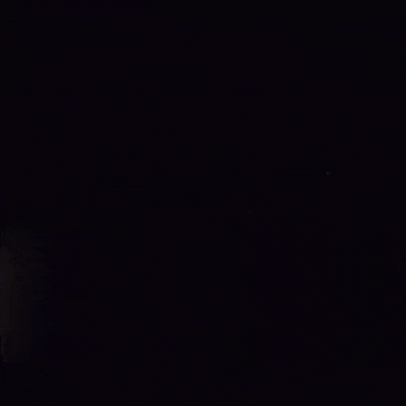 a young man is looking at another young man 's face in a dark room